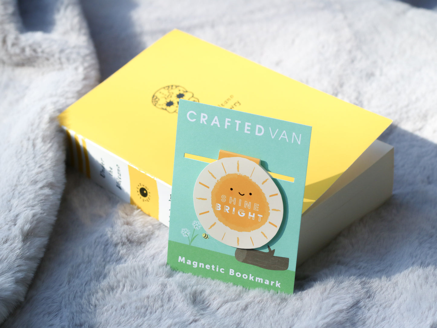Shine Bright Sunshine Magnetic Bookmark by Craftedvan, in it's packaging and alongside a book.